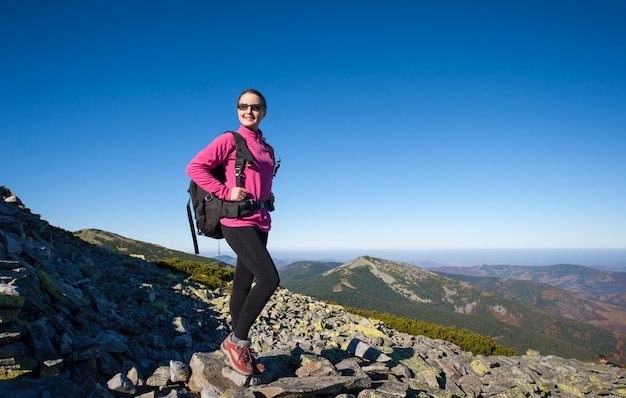 Mochileiro de mulher no pico da montanha rochosa