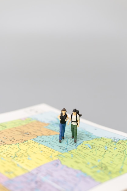 Foto mochileiro de pessoas em miniatura caminhando no mapa de conceitos de viagens e aventura.