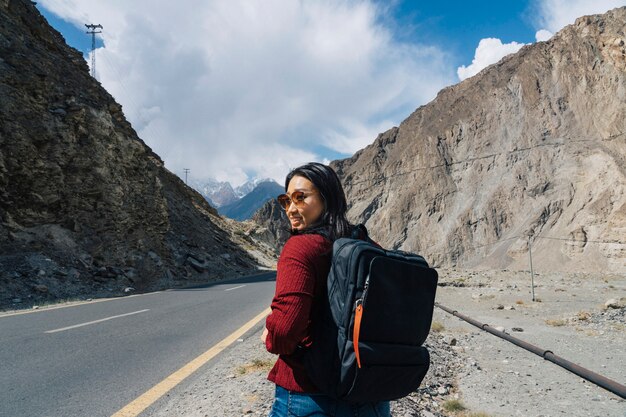 Mochileiro feminino andando em uma estrada montanhosa