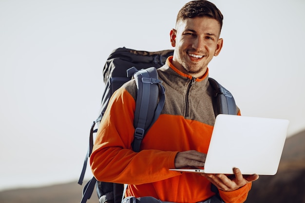 Mochileiro jovem usando seu laptop em uma jornada na montanha