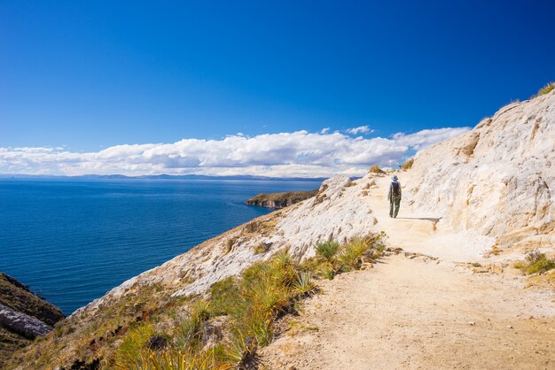 Mochileiro que explora as trilhas incas majestosas na ilha do sol, lago Titicaca, entre o destino o mais cênico do curso em Bolívia. Viagens de aventura e férias nas Américas.