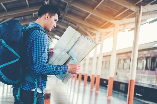 Mochileiro turístico usando o mapa para viajar na estação de trem