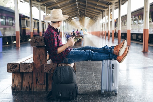 Mochileiros estão sentados para verificar os detalhes da viagem com o mapa enquanto esperam o trem chegar na estação de trem