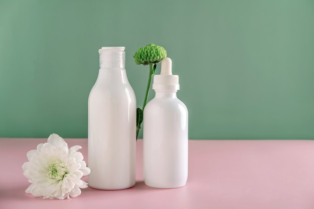 Mock-se cosméticos naturais: soro, creme, máscara para publicidade sobre fundo verde com flores. Produtos orgânicos. Conceito de spa