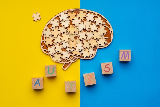 Foto mock-se de um cérebro humano com peças espalhadas em um fundo amarelo e azul. seis cubos com o autismo de inscrição.
