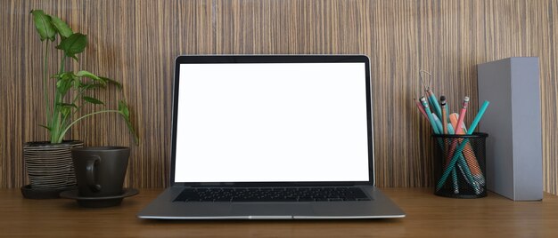 Mock-se imagem de laptop com planta de tela branca, lápis e xícara de café na mesa de madeira.