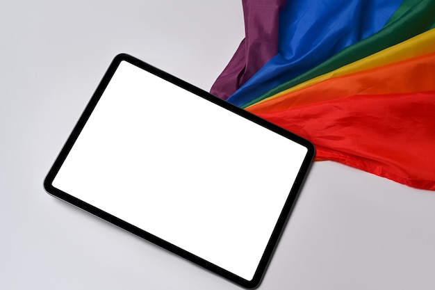 Foto mock-se tablet digital com tela em branco perto da bandeira do arco-íris em fundo branco.
