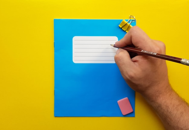 Foto mock up azul cuaderno y tope de libro de texto para materias escolares, borrador, lápiz, clip de papel sobre un fondo amarillo. endecha plana, espacio de copia, vista superior, lugar para texto.