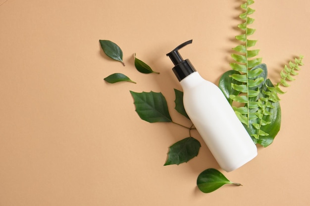 Mock-up-Bio-Kosmetik-Plastikflasche mit Spender und grünen Blättern