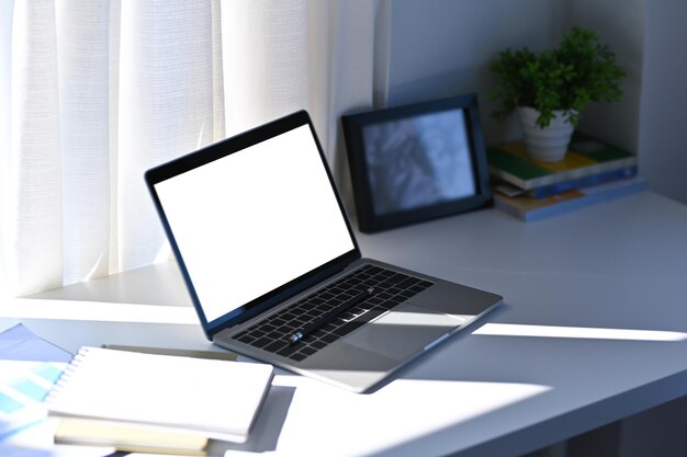 Mock-up-Computer, Buch und Zimmerpflanze auf weißem Tisch im Home Office.