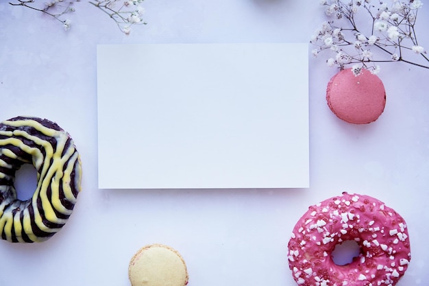 Mock-up der Schreibwarenkarte auf violetter Vintage-OberflächeHelle bunte Makronen Donuts und Gypsophila