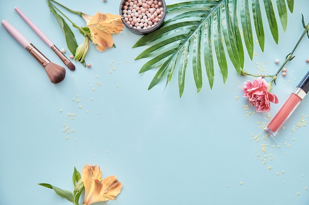 Mock up escovas de garrafas de produtos cosméticos para maquiagem em pó e flores Conceito de beleza Vista superior cópia espaço fundo azul Foto de alta qualidade