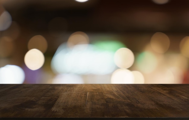 Foto mock up para el espacio mesa de madera oscura vacía frente al fondo de bokeh borroso abstracto del restaurante se puede utilizar para exhibir o montar su producto