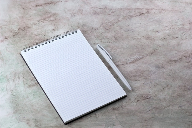 Foto mock up folha de caderno em branco aberto e fundo de mármore de caneta