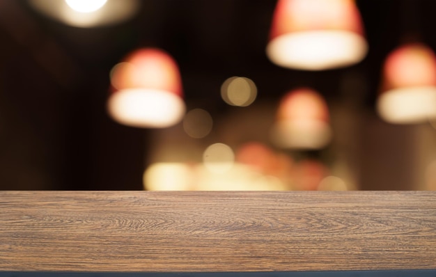 Mock-up für den Raum Leerer dunkler Holztisch vor dem abstrakten verschwommenen Bokeh-Hintergrund des Restaurants kann zur Anzeige oder Montage Ihres Produkts verwendet werden