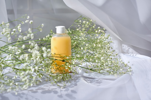Mock-up-Gel- oder Shampoo-Flasche und Schleierkrautblüten auf weißer Szene