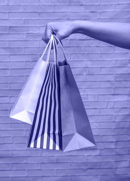 Mock-up-Öko-Verpackungsnahaufnahme auf einem Ziegelstein sehr peri-Hintergrund. Kraftbeutel in schwarz-weiß gestreift, weiß, Handwerk in der Hand einer Frau. Online-Shopping-Konzept, Lieferung, Online-Bestellungen.