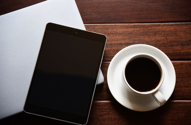 mock up tablet tela em branco e xícara de café na mesa no interior em casa escritório