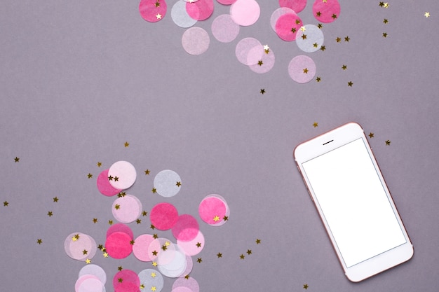 Foto mock up de teléfono móvil y confeti rosa con estrellas doradas en gris