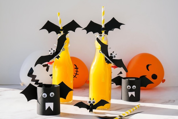 Mocktails de Halloween Coquetel não alcoólico de laranja Festa de Halloween na mesa branca Canudos cortam morcegos de papel