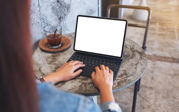 Mockup-Bild einer Frau, die auf einem digitalen Tablet mit leerem weißen Desktop-Bildschirm als Computer-PC auf dem Tisch im Café tippt