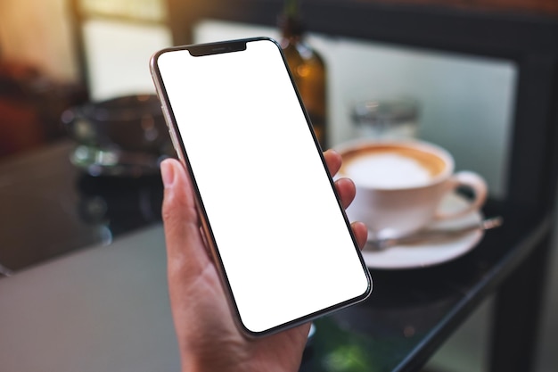 Mockup-Bild einer Frau, die ein Handy mit einem leeren weißen Desktop-Bildschirm hält