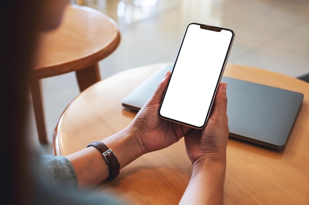 Mockup-Bild einer Frau, die ein Mobiltelefon mit einem leeren weißen Desktop-Bildschirm hält