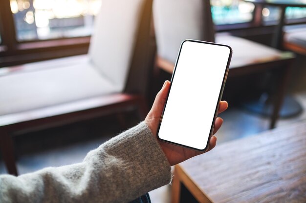 Mockup-Bild einer Frau, die ein Mobiltelefon mit einem leeren weißen Desktop-Bildschirm hält