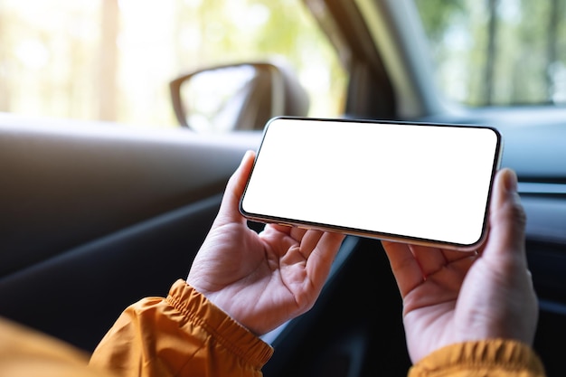 Mockup-Bild einer Frau, die ein Mobiltelefon mit leerem Bildschirm im Auto hält und benutzt