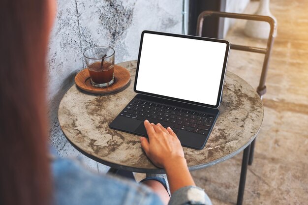 Mockup-Bild einer Frau, die ein Tablet-Touchpad mit einem leeren weißen Desktop-Bildschirm als Computer-PC auf dem Tisch im Café berührt