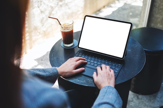 Mockup-Bild einer Frau, die eine Tablet-Tastatur mit leerem weißem Desktop-Bildschirm als Computer-PC mit Kaffeetasse auf dem Tisch verwendet und tippt