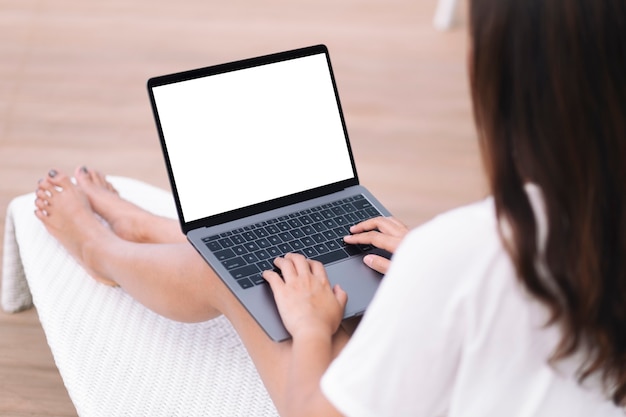 Mockup-Bild einer Frau, die einen Laptop verwendet und tippt, während sie auf der Terrasse sitzt