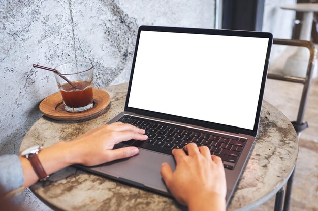 Mockup-Bild einer Frau, die im Café eine Laptop-Computertastatur mit einem leeren weißen Desktop-Bildschirm verwendet und darauf tippt