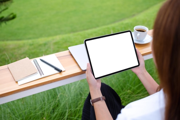 Mockup-Bild einer Frau, die im Freien ein digitales Tablet mit einem leeren weißen Desktop-Bildschirm hält