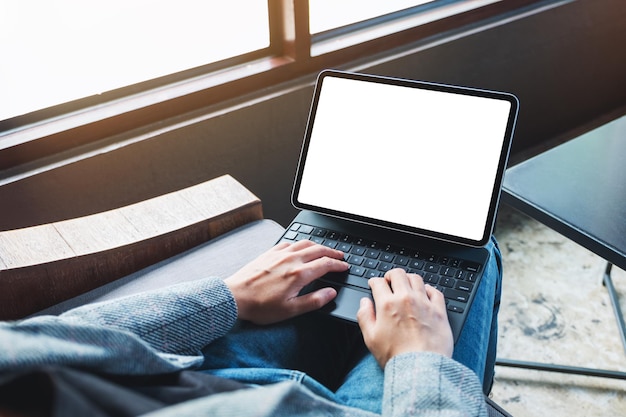 Mockup-Bild einer Frau, die Tablet-Tastatur mit leerem weißem Desktop-Bildschirm als Computer verwendet und tippt