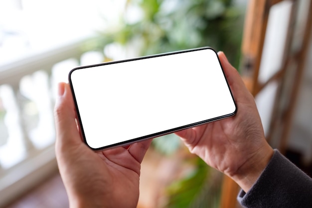 Mockup-Bild einer Frau, die zu Hause auf dem Balkon ein Handy mit leerem Desktop-Bildschirm hält