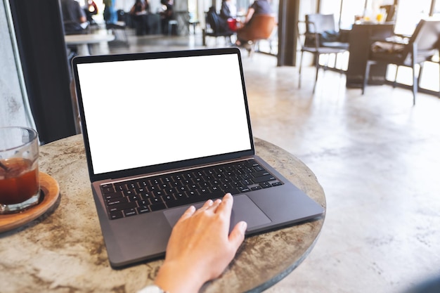 Mockup-Bild einer Hand, die das Touchpad eines Laptops mit einem leeren weißen Desktop-Bildschirm auf dem Tisch berührt