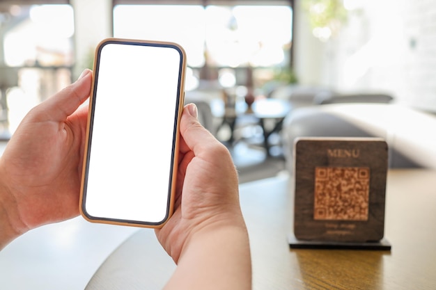 Foto mockup-bild von frauenhänden, die ein weißes handy mit leerem bildschirm im café halten