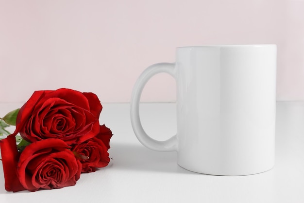 Mockup einer weißen Keramikkaffeetasse mit einem Strauß roter Rosen, Vorderansicht
