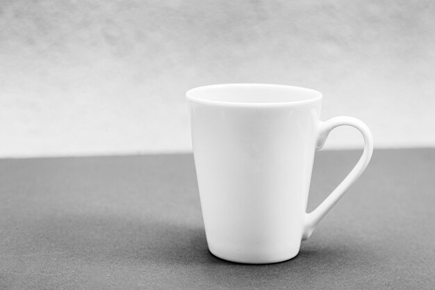 Foto mockup en forma de una taza blanca sobre un fondo blanco y negro descolorido