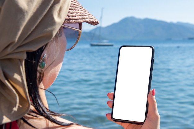 Mockup Handy Seeurlaub. Frau Hand hält Handy mit leerem Bildschirm gegen Sea Beach Outdoor. Roaming im Urlaub