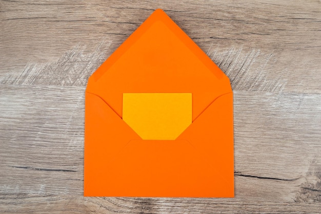 Mockup mit einer Karte in einem orangefarbenen Umschlag Ansicht von oben Leerer Aufkleber in einem Umschlag auf dem Tisch