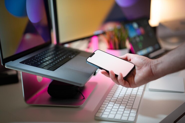 Foto mockup de pantalla blanca vacía con el teléfono inteligente en la mano interior de la oficina del estudio de la casa