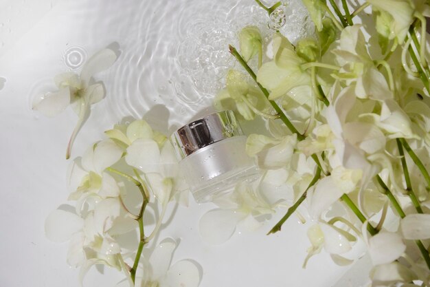 Mockup-Röhrenflasche für Hautpflegekosmetik mit Wasserspritzer und Blumenprodukt-Branding-Serum-Tropfcreme-Lotionsbehandlung