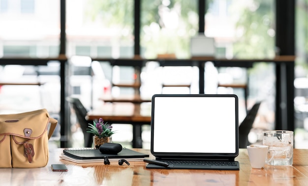 Mockup-Tablette mit leerem Bildschirm mit Tastatur und Gadget auf Holztisch im Café.