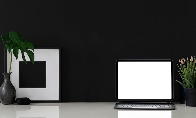 Mockup-Tablette mit leerem Bildschirm mit Tastatur und schwarzem Holzrahmen auf weißem Tisch, schwarzer Farbhintergrund.