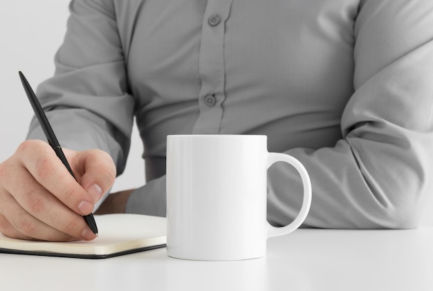 Mockup de taza blanca con hombre tomando notas