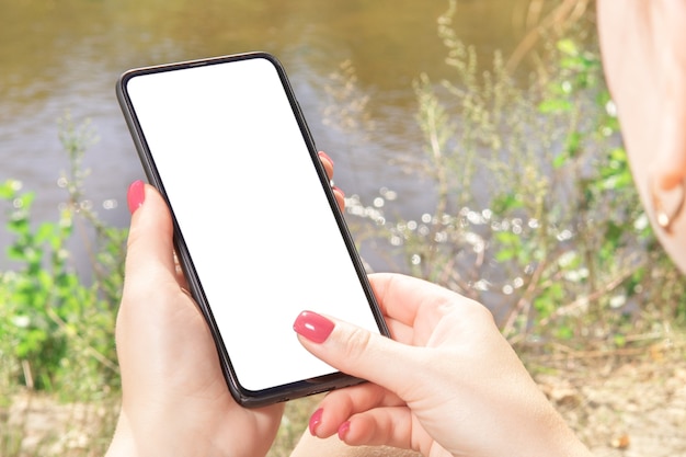 Mockup-Telefon. Nahaufnahme Handberührung auf Handy-Handy leeren schwarzen Bildschirm im Freien auf verschwommene Natur