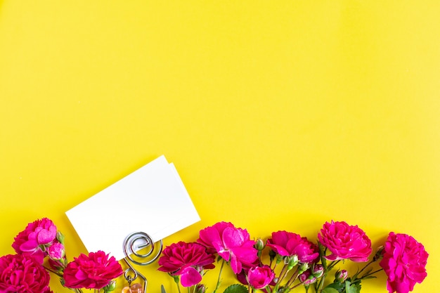 Mockup Visitenkarten auf einem farbigen Hintergrund und einer Rosenblume, Copyspace, Draufsicht.