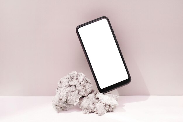 Foto mockup-vorlage für ein smartphone, das auf naturstein auf rosa hintergrund balanciert